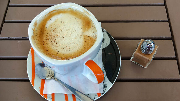 Šolja kafe i cimet u bočici na stolu