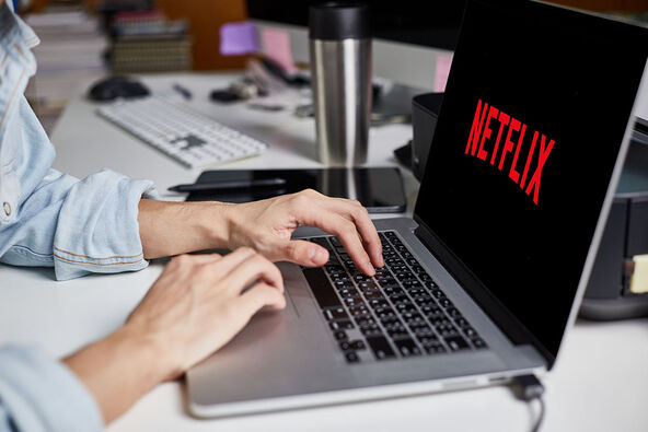 Devojka kuca na laptopu sa natpisom Netflix
