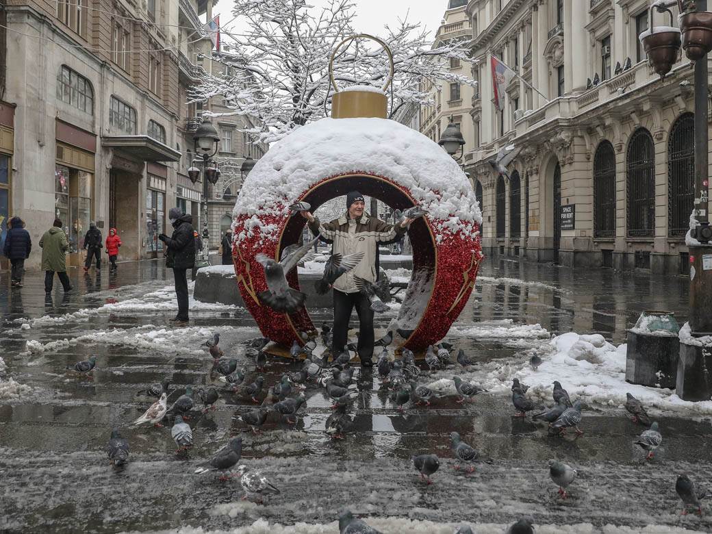 covek hrani golubove u beogradu sneg zima ulica ljudi fotografije