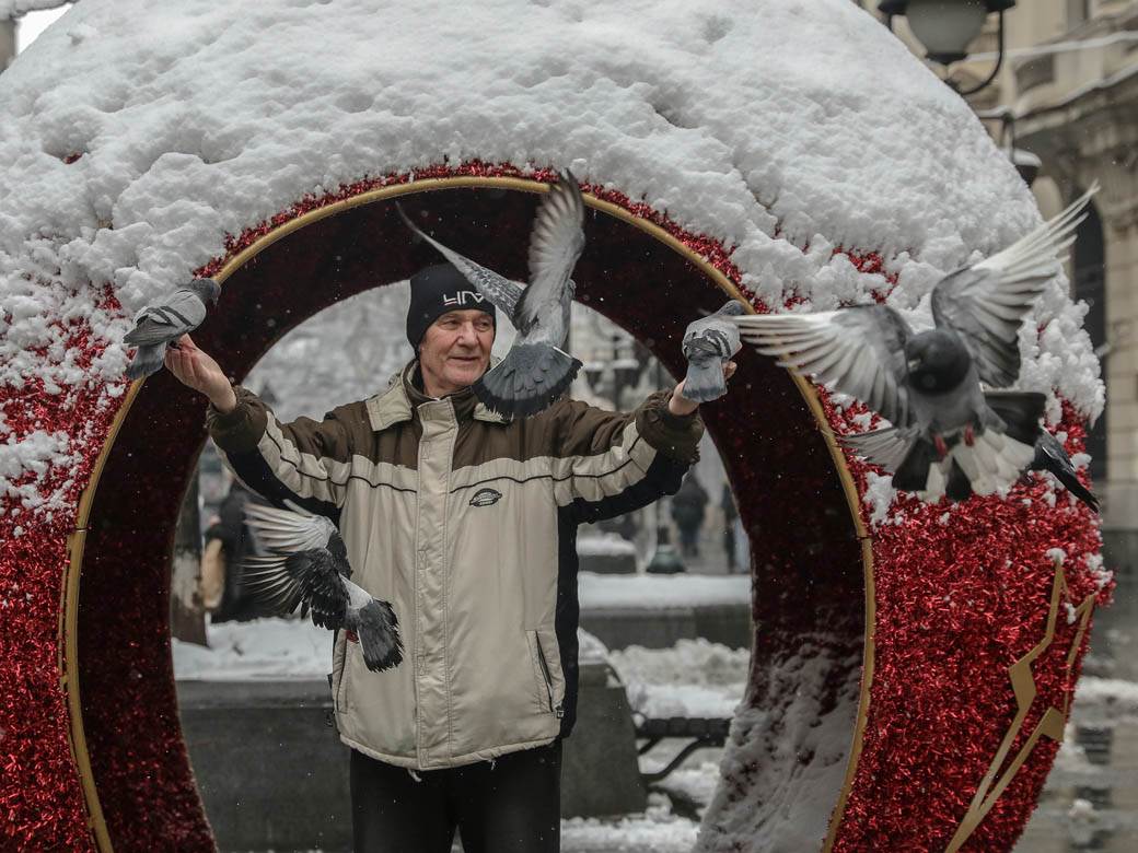 covek hrani golubove u beogradu sneg zima ulica ljudi fotografije
