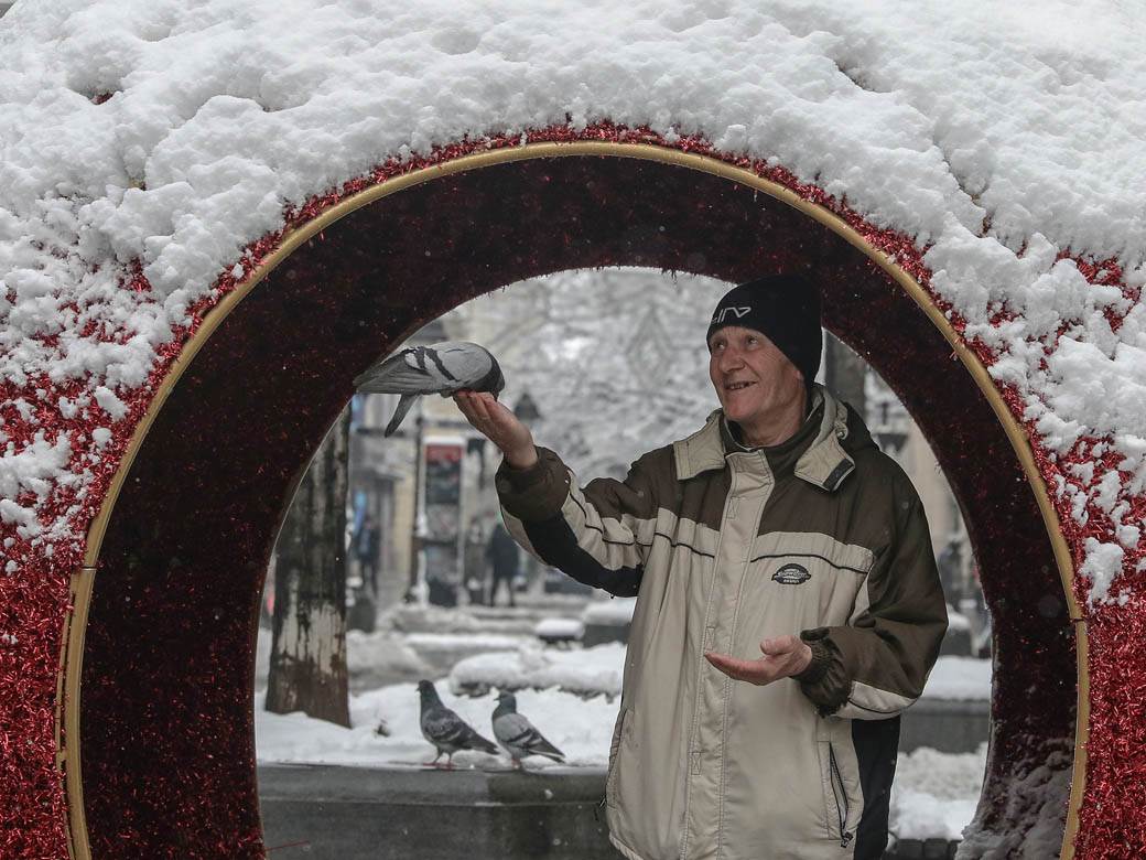 covek hrani golubove u beogradu sneg zima ulica ljudi fotografije