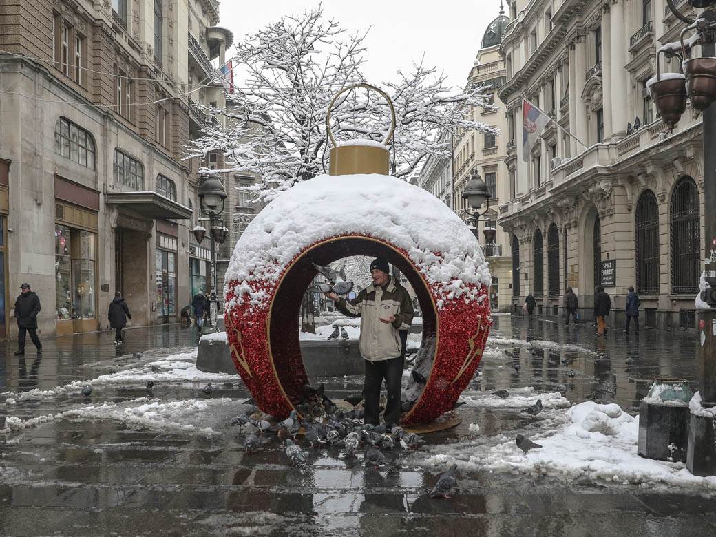 covek hrani golubove u beogradu sneg zima ulica ljudi fotografije