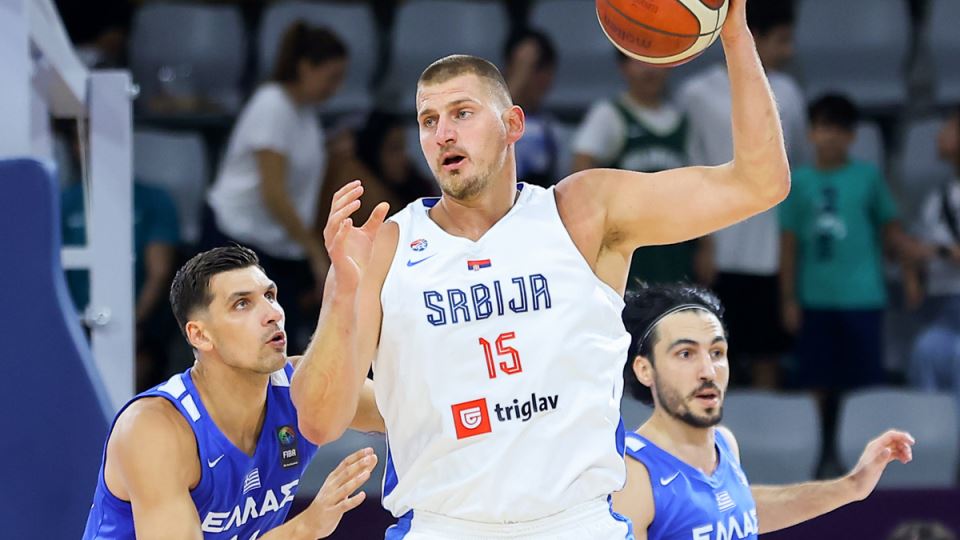 Nikola Jokić u belom dresu Srbije dobija loptu i drži je.